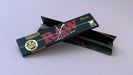 RAW Black - Classic King Size Slim, featuring ultra-thin, unbleached, and double-pressed artisan paper with a tan black and gold red themed packaging. RAW King Size Slim natural unrefined, 110x44mm, 32 leaves per booklet.