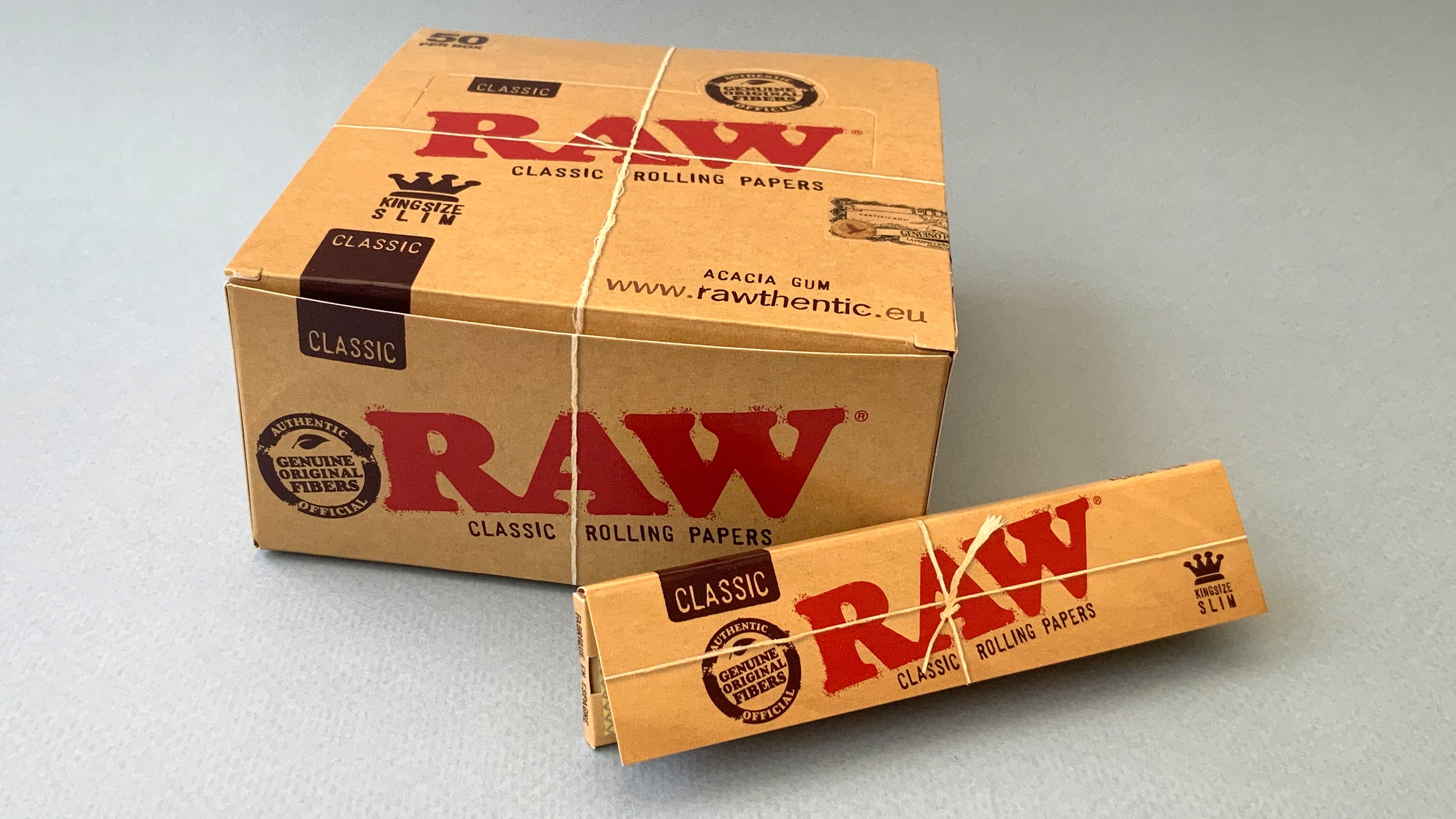 RAW Black - Classic King Size Slim, featuring ultra-thin, unbleached, and double-pressed artisan paper with a tan black and gold red themed packaging. RAW King Size Slim natural unrefined, 110x44mm, 32 leaves per booklet.